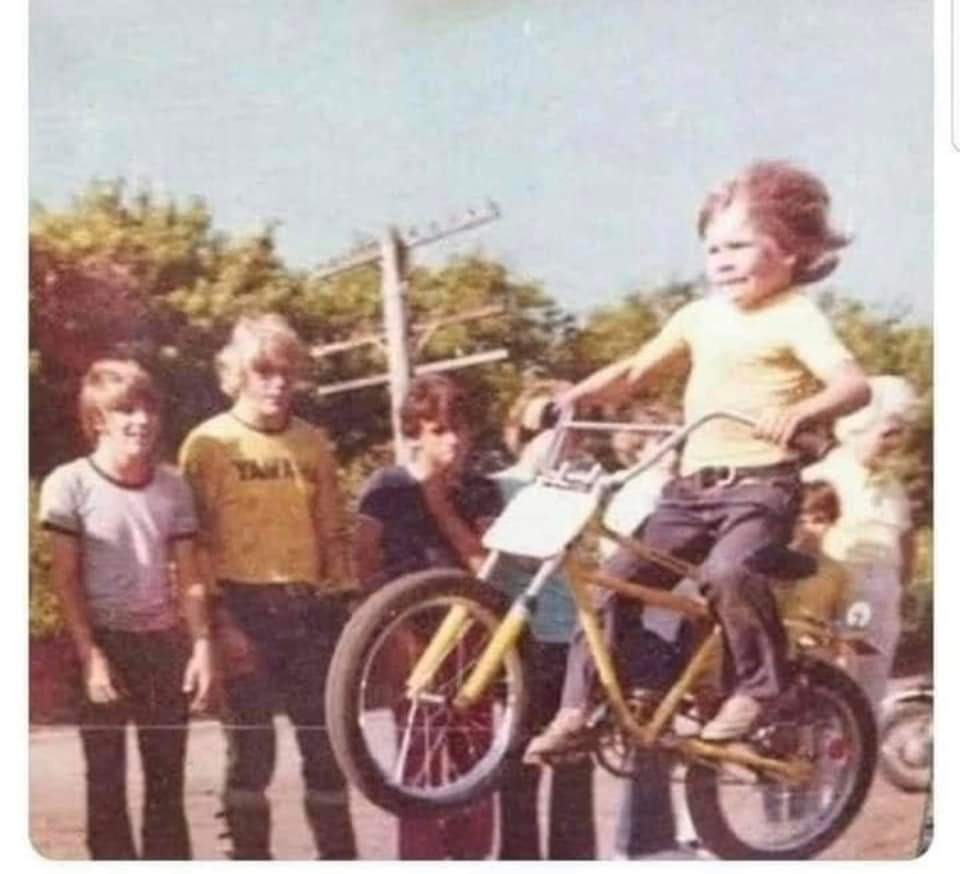 Original low-resolution snapshot of a child on a yellow BMX bike with friends